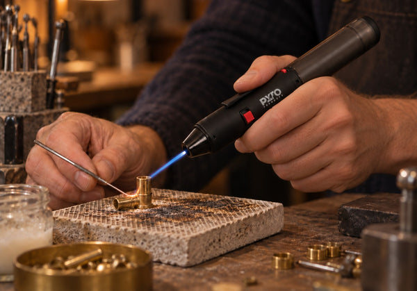 Gas torch soldering a copper joint on a soldering block with a blue jet flame